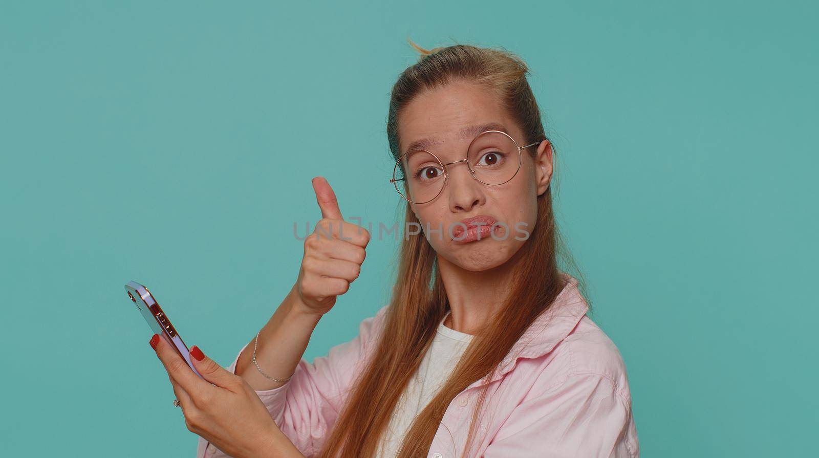 Pretty teen female child kid using smartphone typing new post on web, browsing, searching, addiction of social networks, show thumbs up like, positive feedback, recommends wifi cellular connection 5G