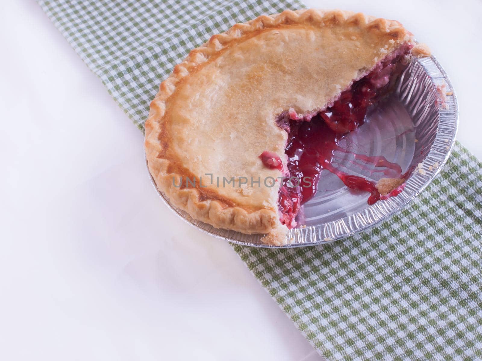 Cherry pie in baking tin with piece missing.