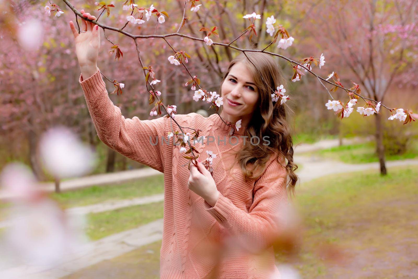 Pretty woman standing under pink blossom branch Sakura . Copy space