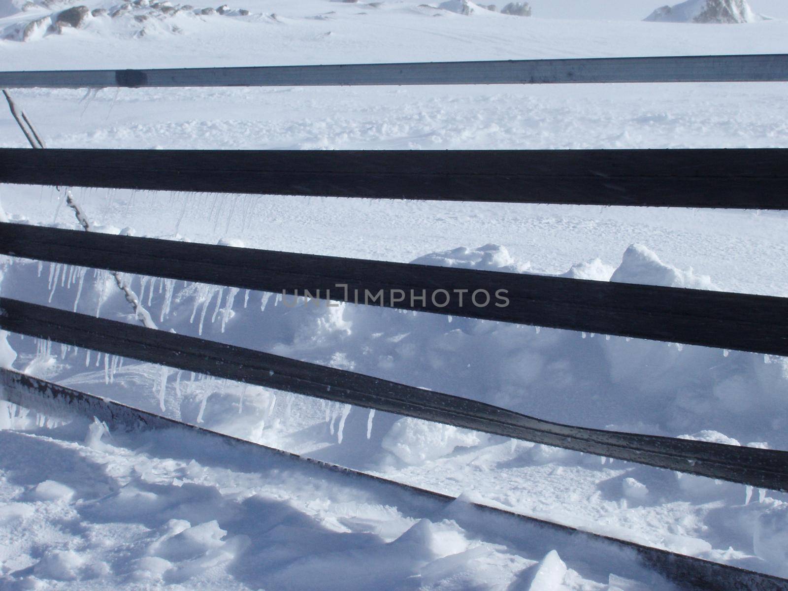 icicles forming on a mountain top snowdrift fence
