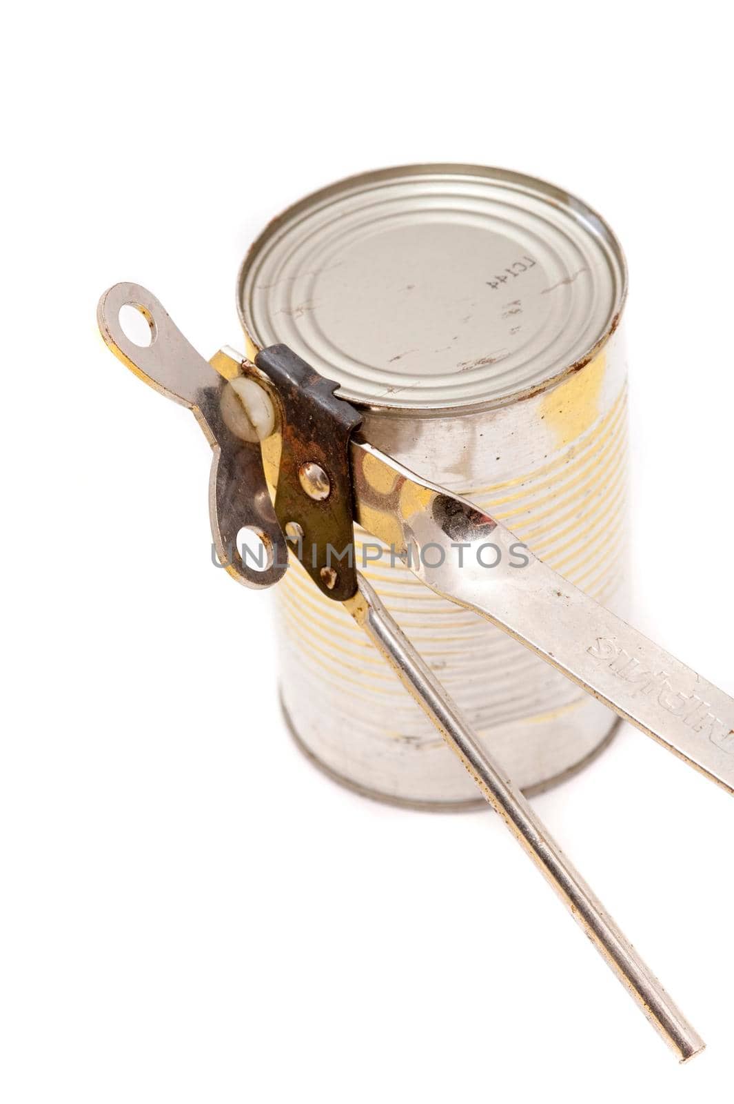 Opening canned vegetables with a manual steel can opener over a white background, close up view of an unlabelled can