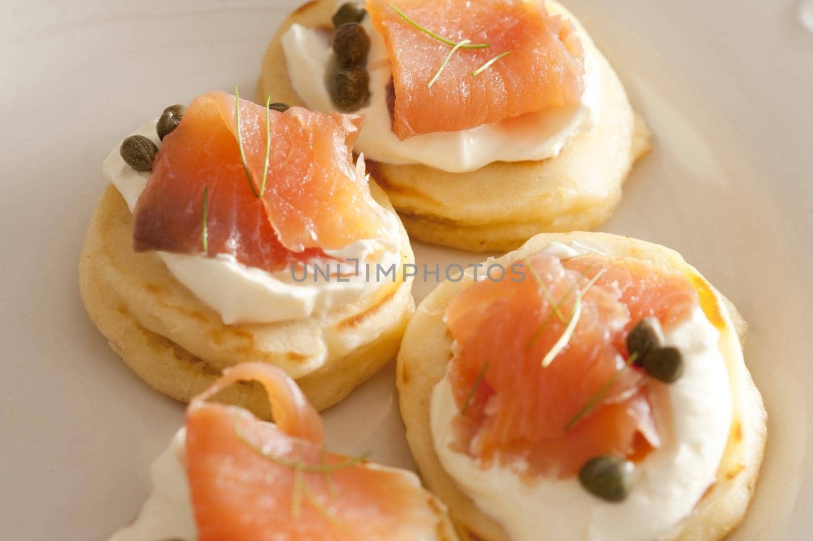 Selective focus cropped close up on lox biscuit snacks topped with capers and white sour cream or cheese