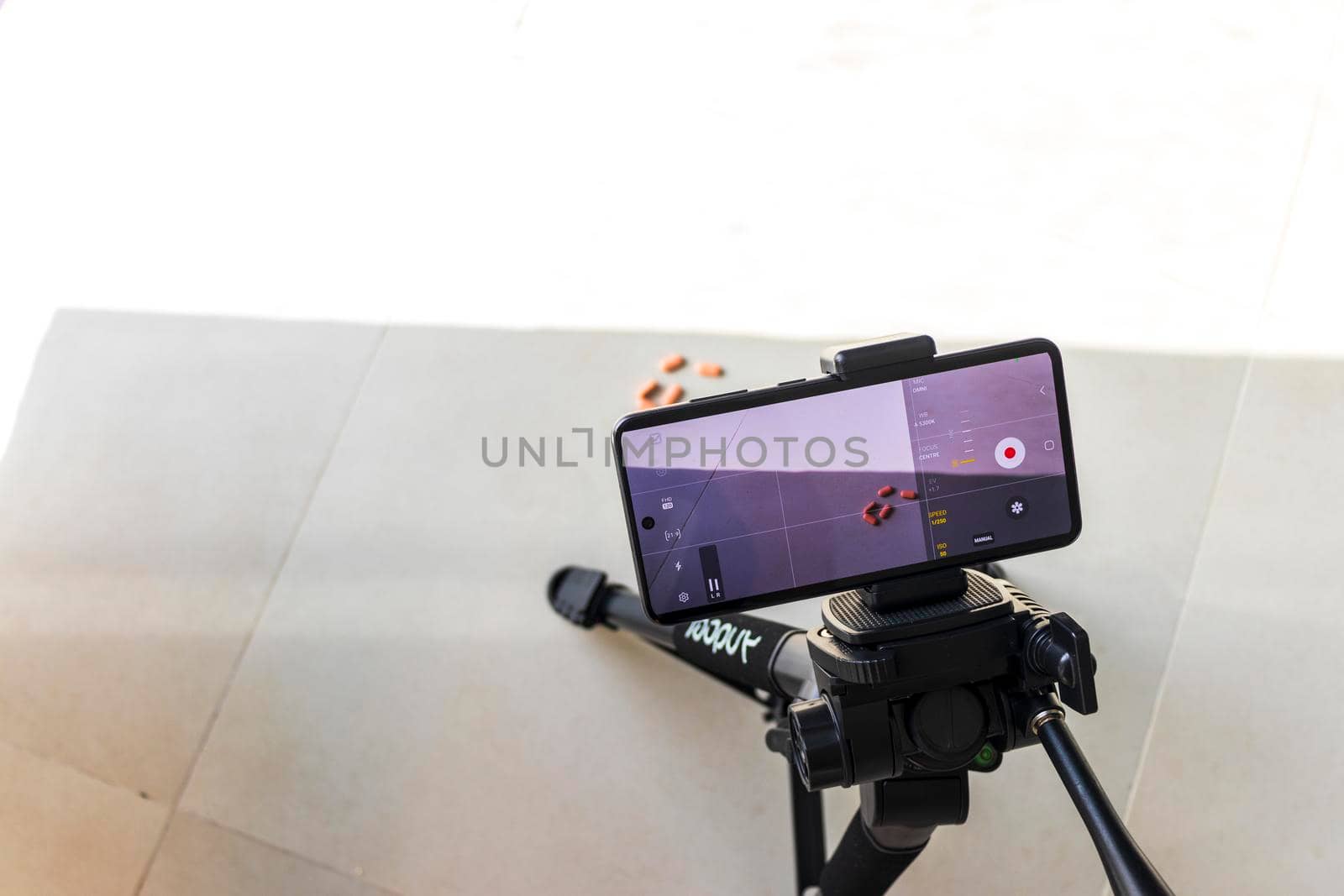 Close up shot of a phone on tripod capturing medicine on the surface