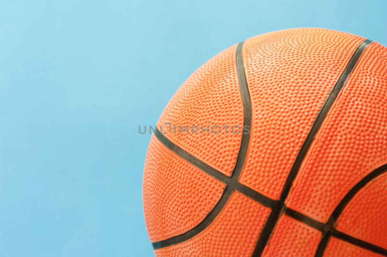 Close up Textured Orange Basketball Ball with Black Lines Isolated on a Sky Blue Background