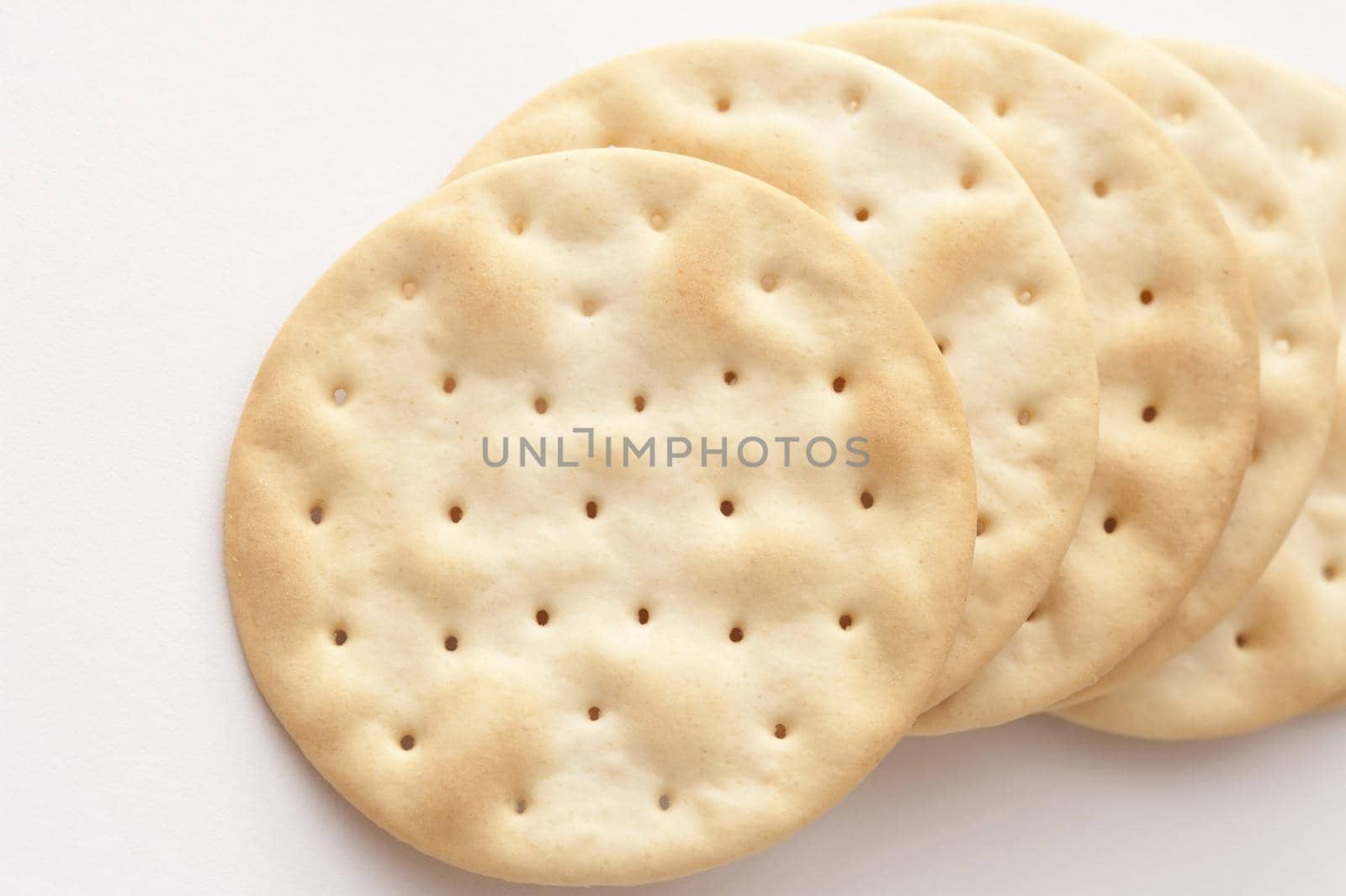 Close-up of several crusty crackers lying on white background