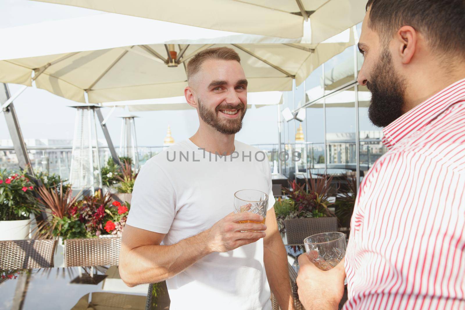 Cheerful handsome bearded man smiling to the camera enjoying rooftop summer party