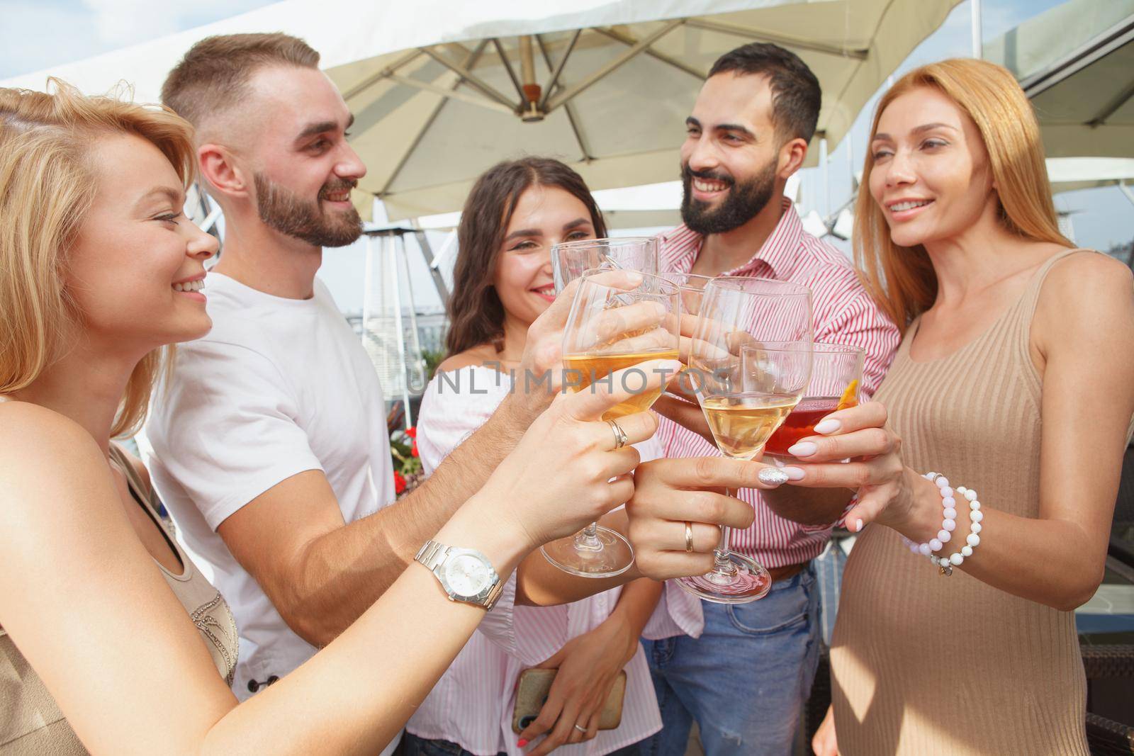 Selective focus on wine glasses in the hands of group of friends toasting during party