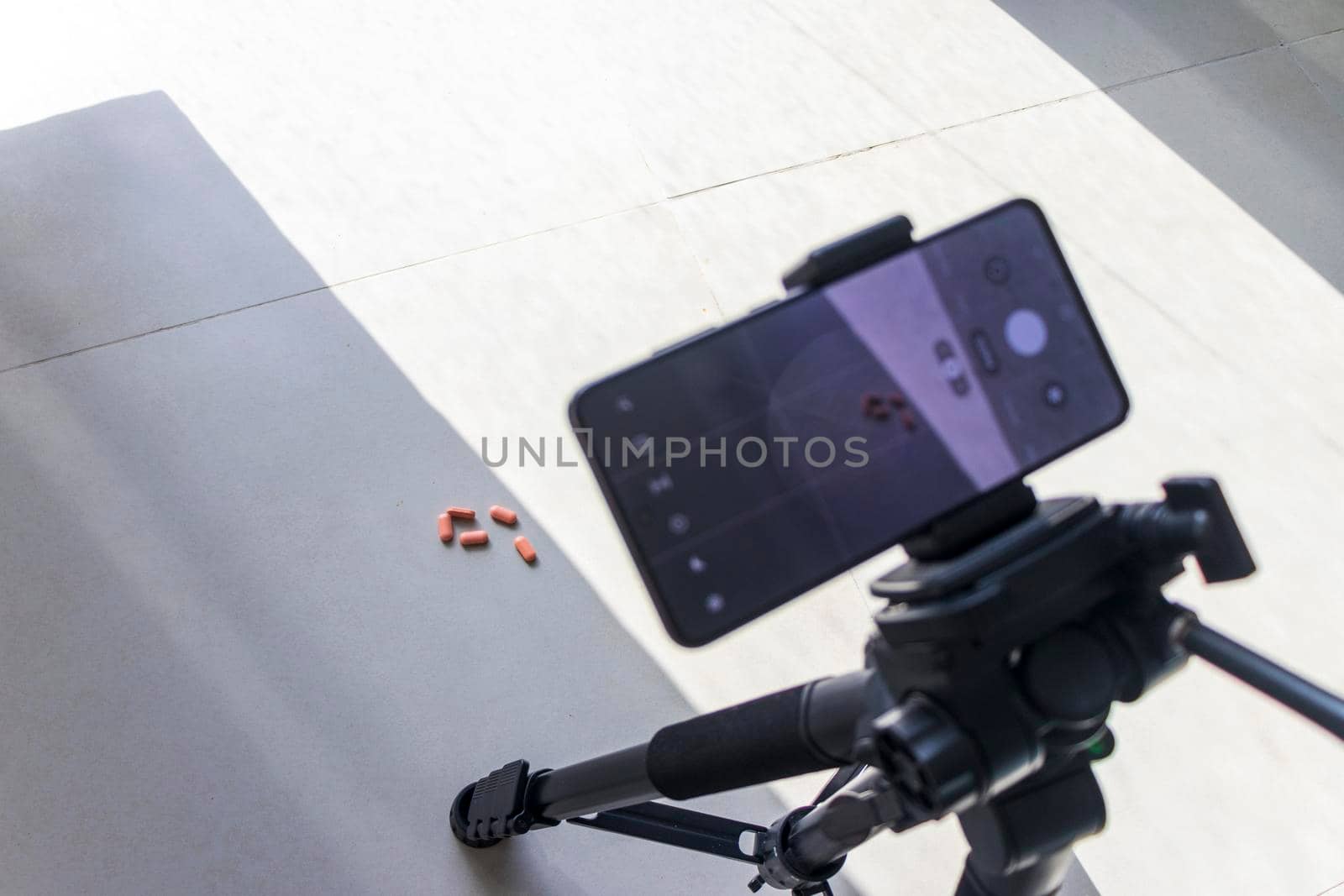 Close up shot of a phone on tripod capturing medicine on the surface. Technology by pazemin