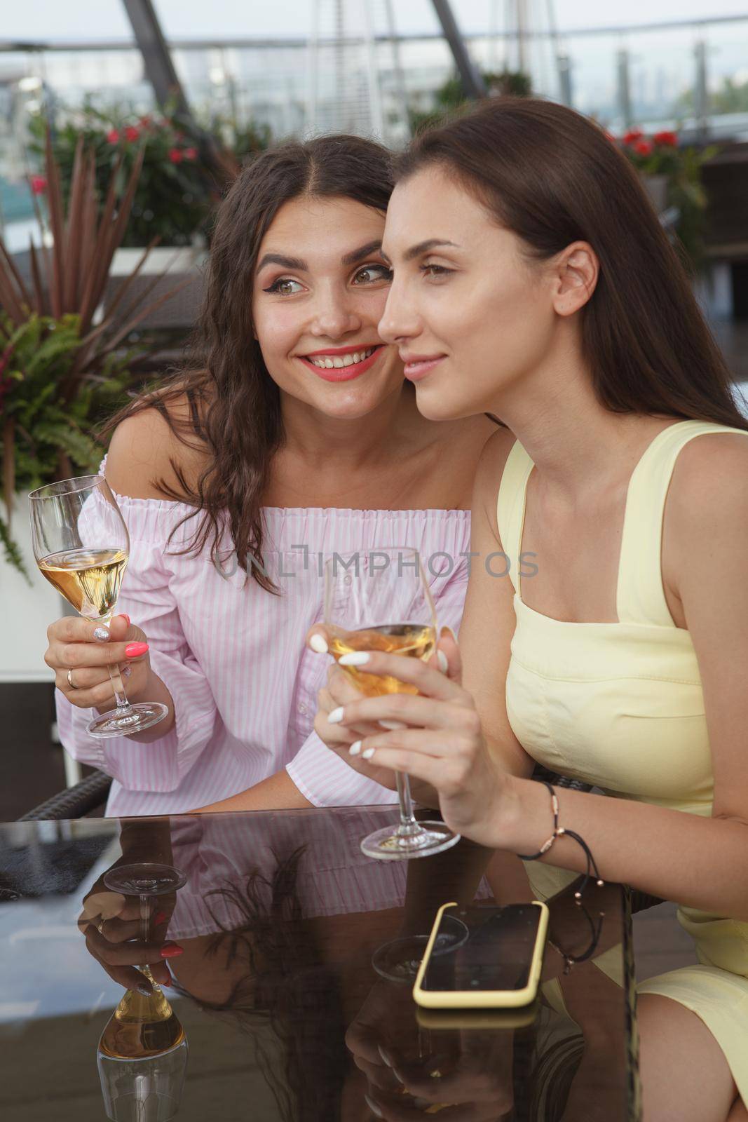 Female friends enjoying drinks on bar terrace by MAD_Production