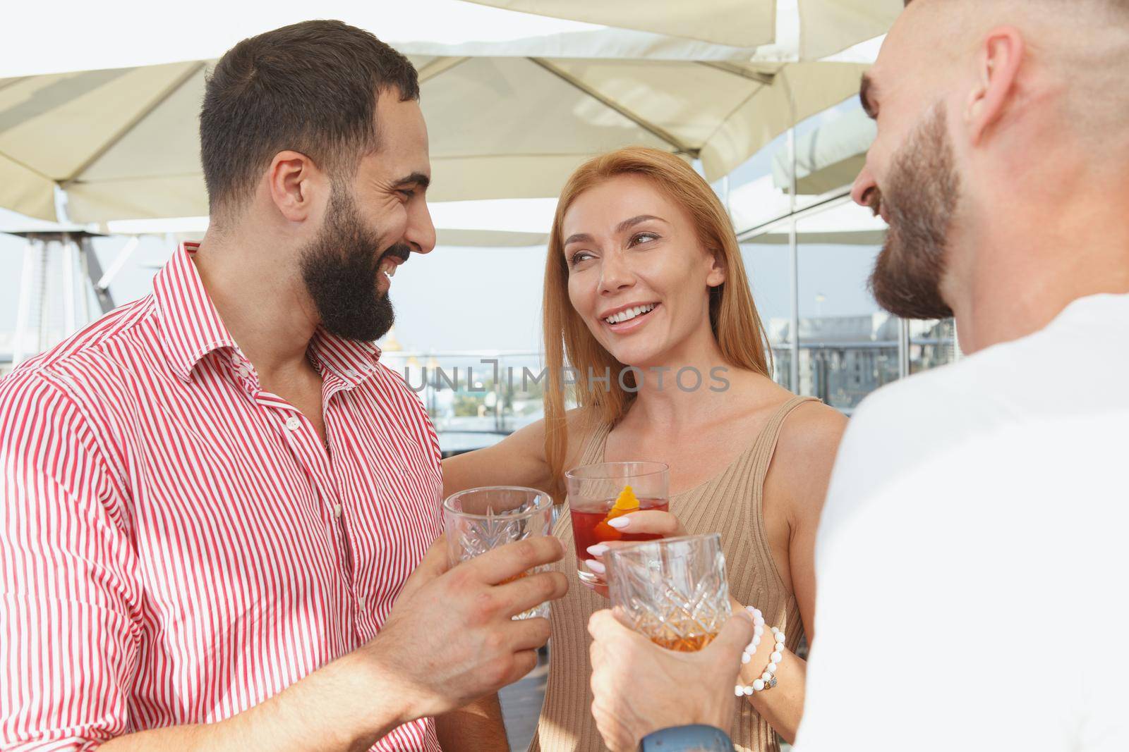 Beautiful woman talking to her male friends over drinks on a rooftop party