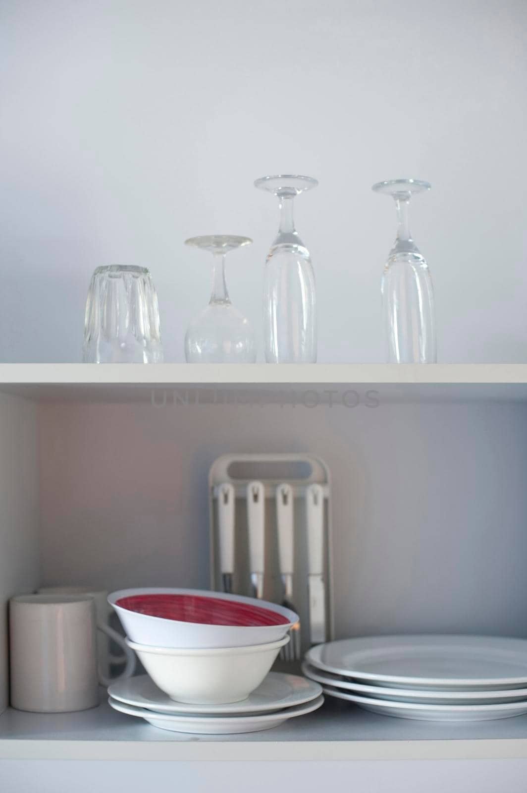 Open kitchen shelves stacked neatly with stored crockery, cutlery and glassware