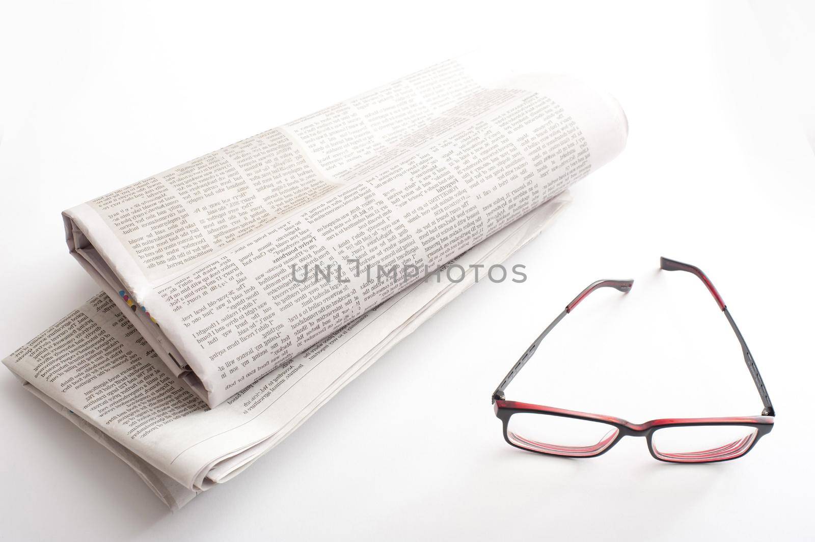 Reading newspapers concept with a pair of glasses and two folded fresh newspapers on white table surface in close-up