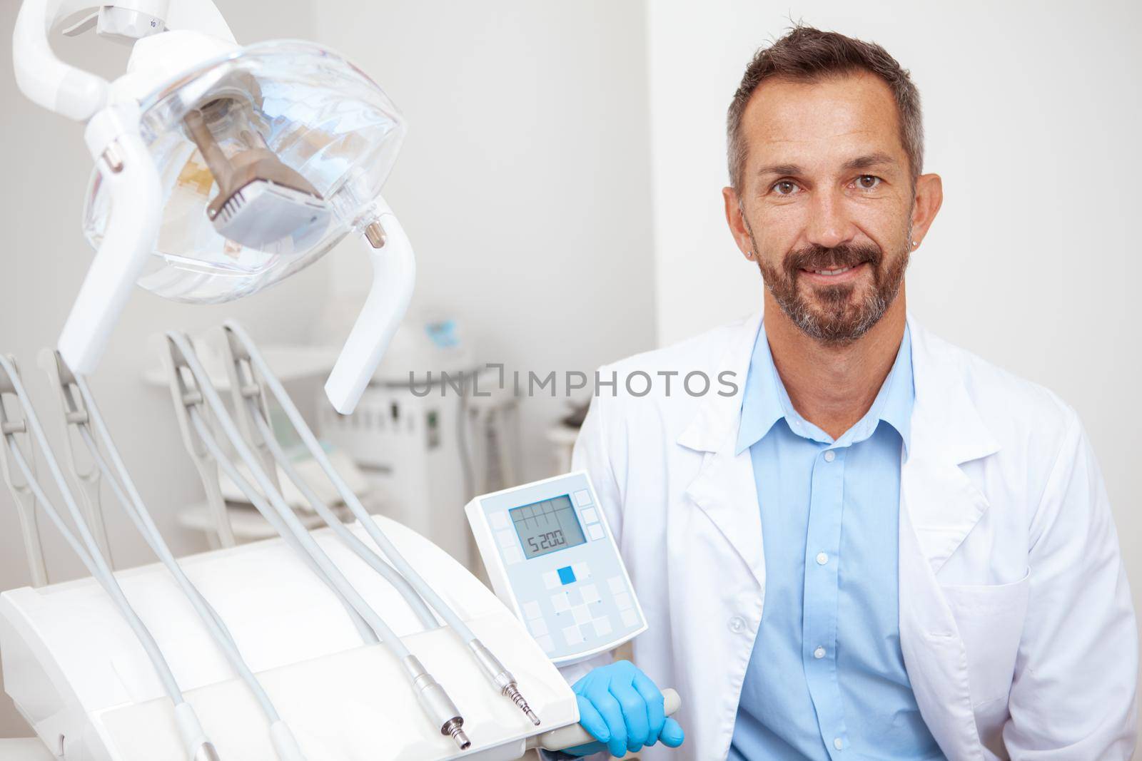 Mature male dentist working at his clinic by MAD_Production