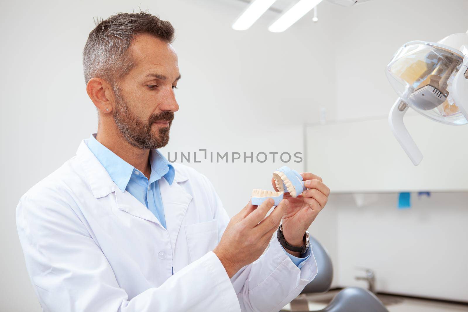 Mature male dentist working at his clinic by MAD_Production