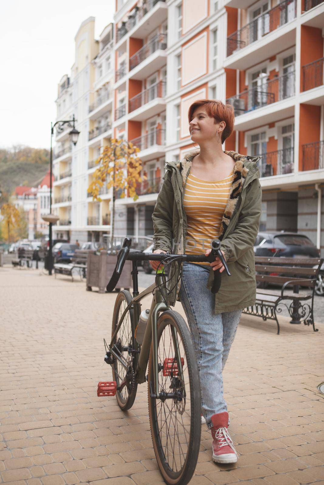 Vertical full length shot of a young woman walking city streets with her bicycle