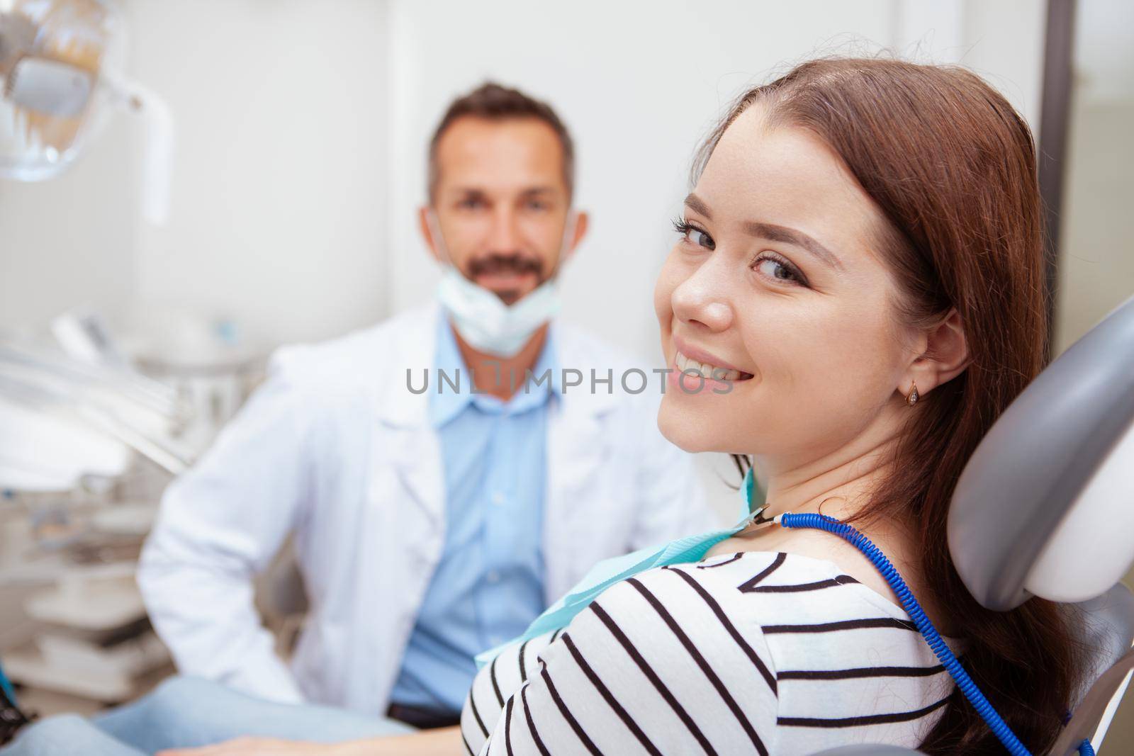 Charming happy woman smiling to the camera, sitting in dental chair after teeth examination