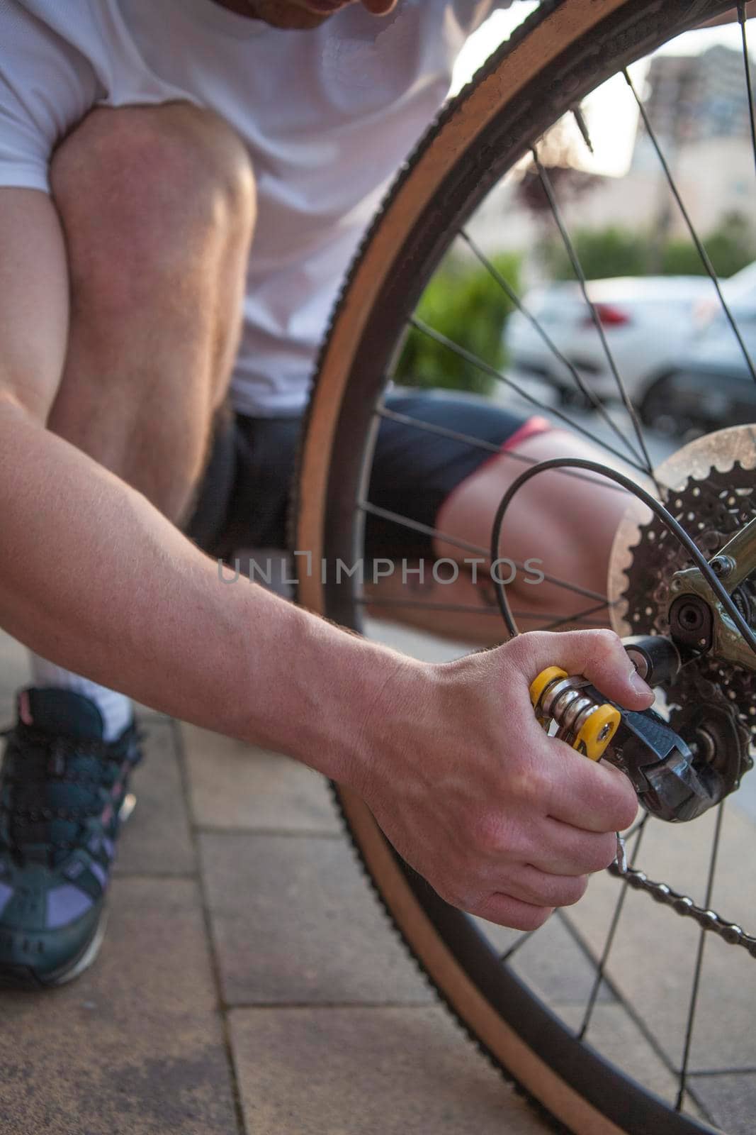 Vertical shot of a man using multitool to repair his bicycle