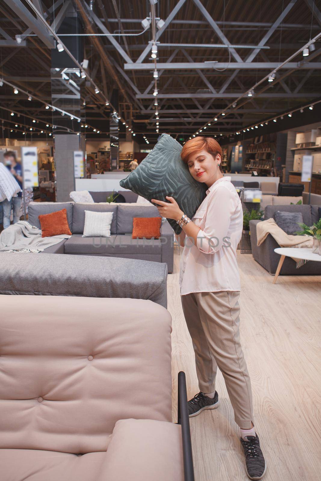 Vertical shot of a female customer trying soft cushion, shopping at furniture store