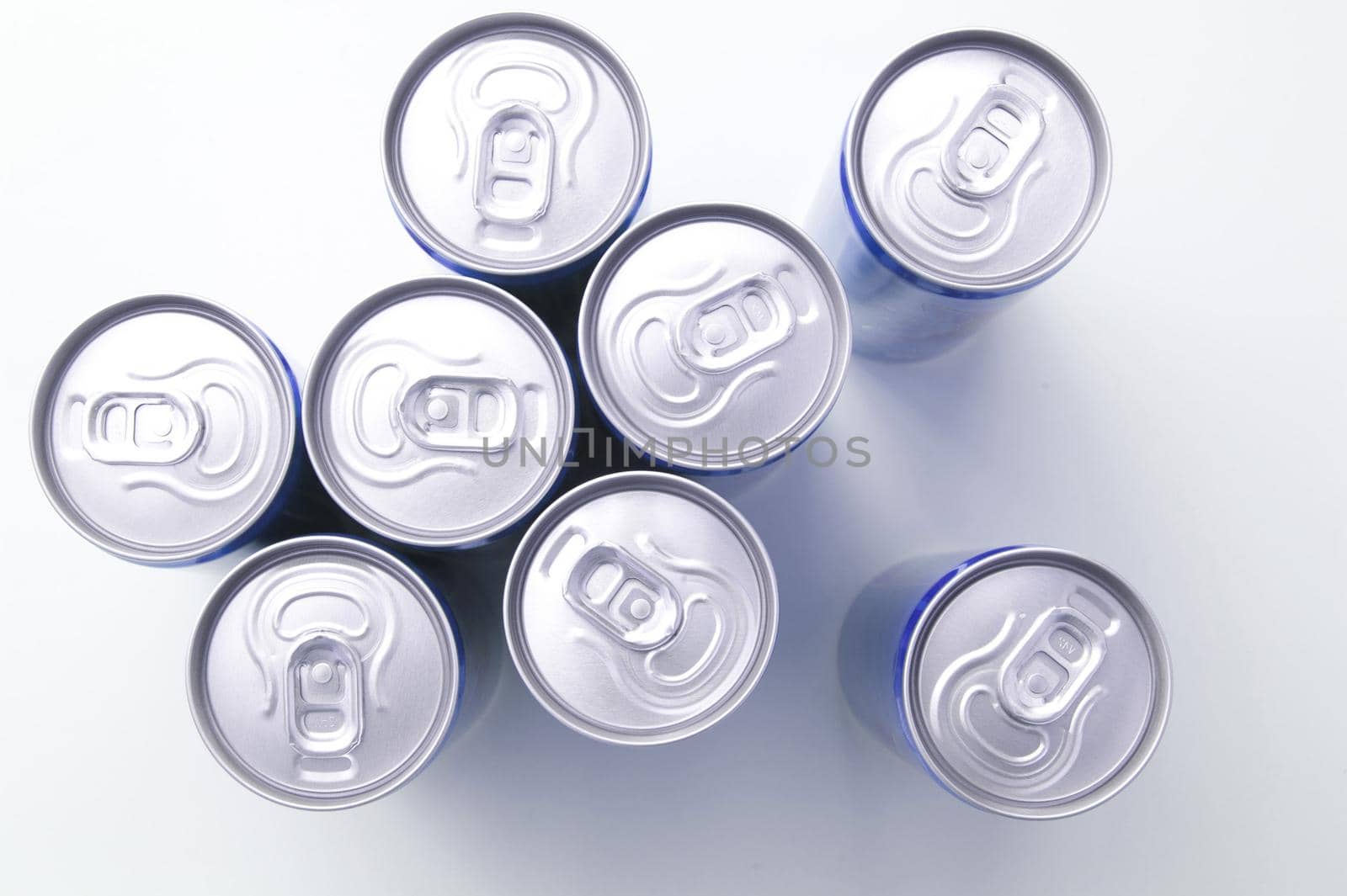 Unopened drinks cans viewed from above looking down onto the aluminium lids over a white background