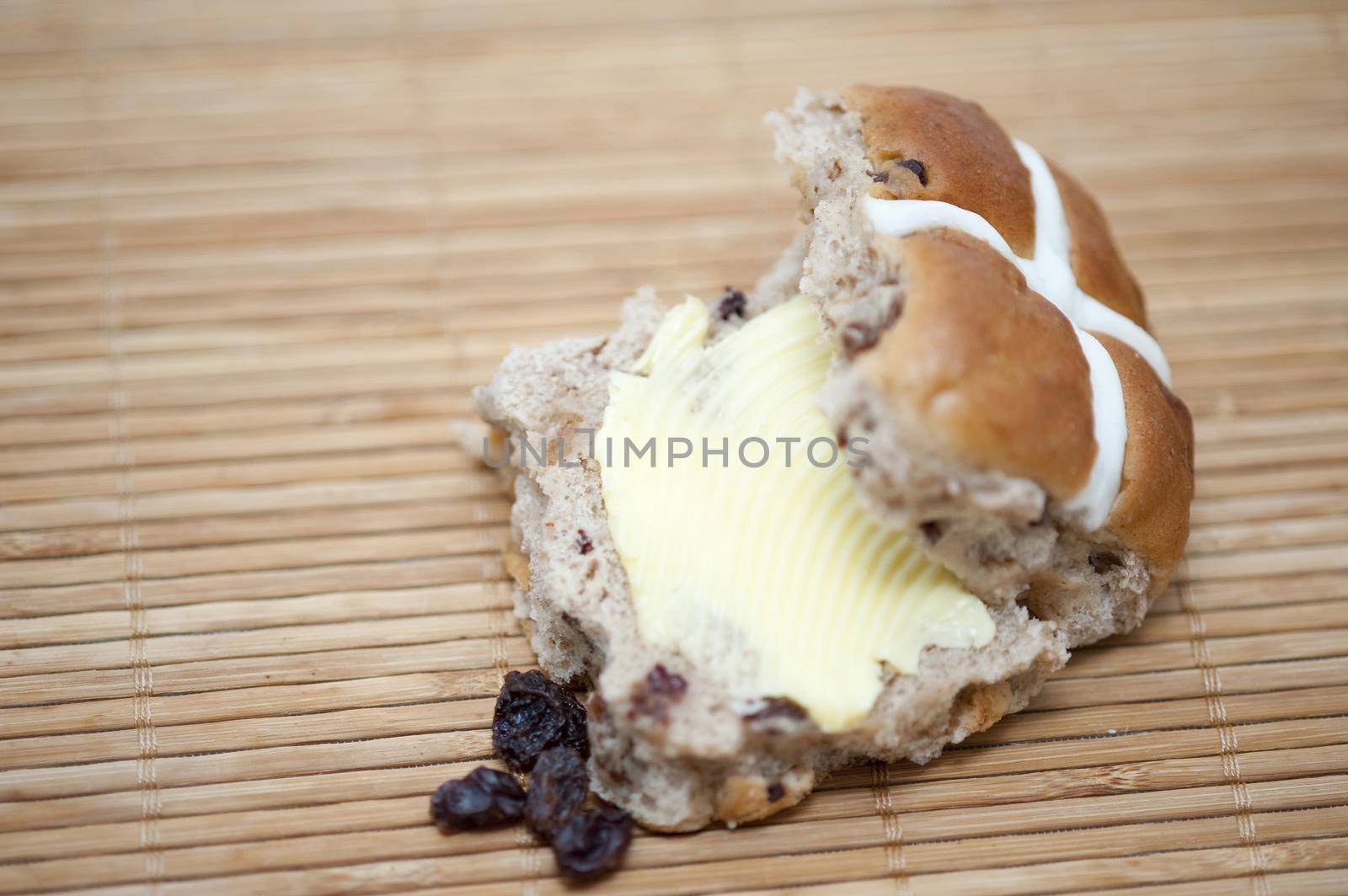 Delicious buttered fresh spicy Easter Hot Cross Bun with raisins