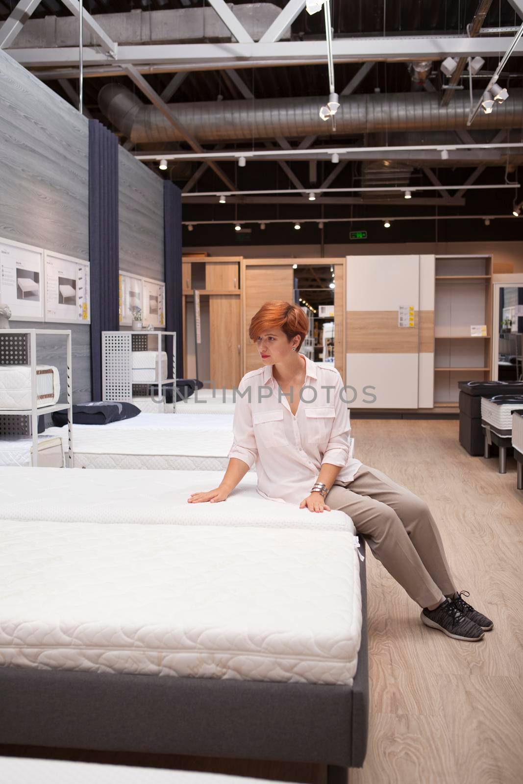 Vertical full length shot of a young woman trying new orthopedic bed at furniture store