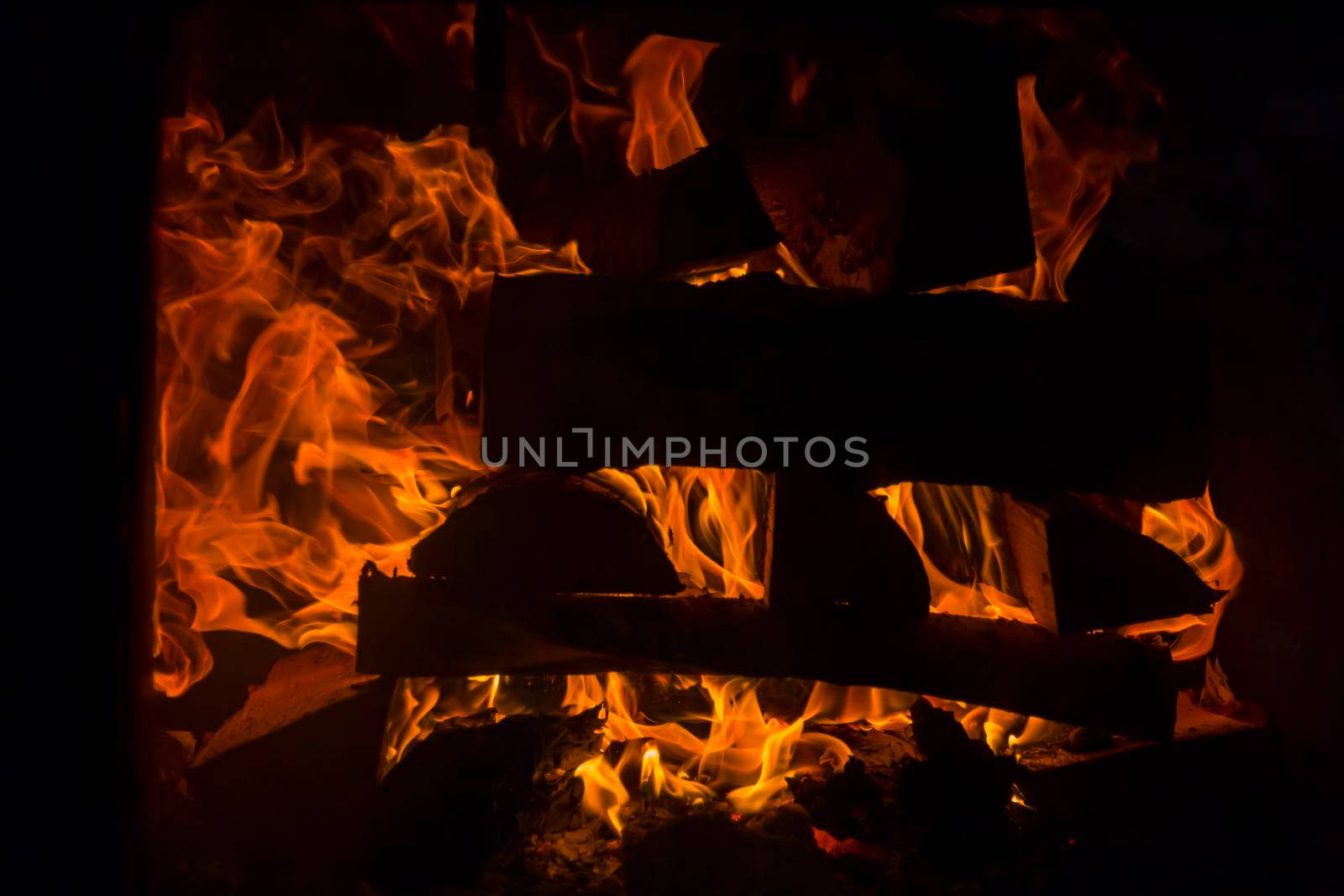 The firewood is burning with an orange fire in the fireplace. Heating of the house without electricity..