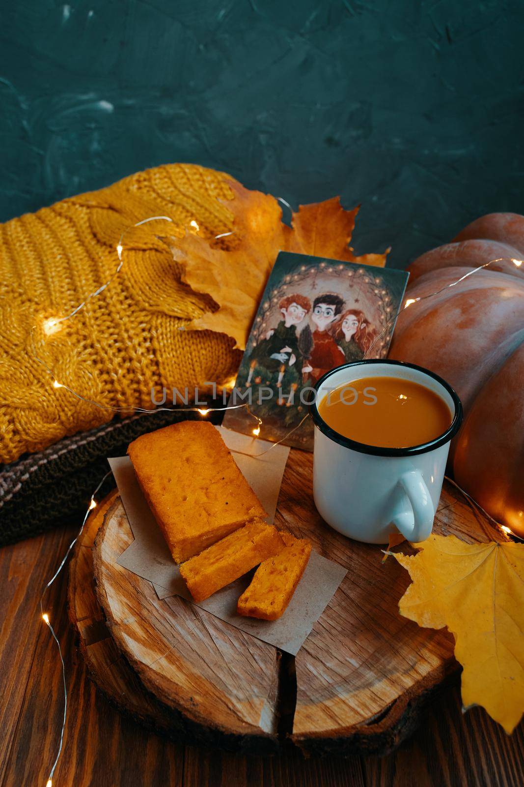 Autumn composition for posters. Carrot cake, pumpkin juice, fall leaves, sweater, scarf, pumpkin, postcard with Harry Potter and garland on wooden background. Bishkek, Kyrgyzstan - November 1, 2019.