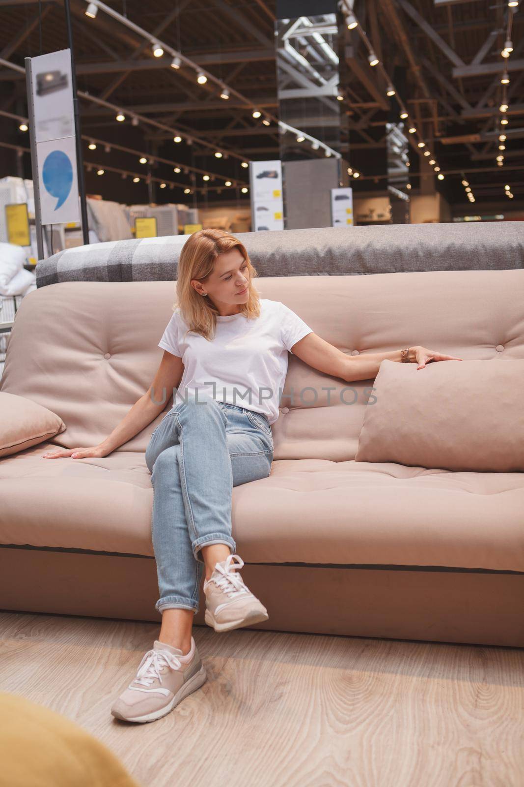 Vertical shot of a mature attractive woman sitting on a couch at furniture store