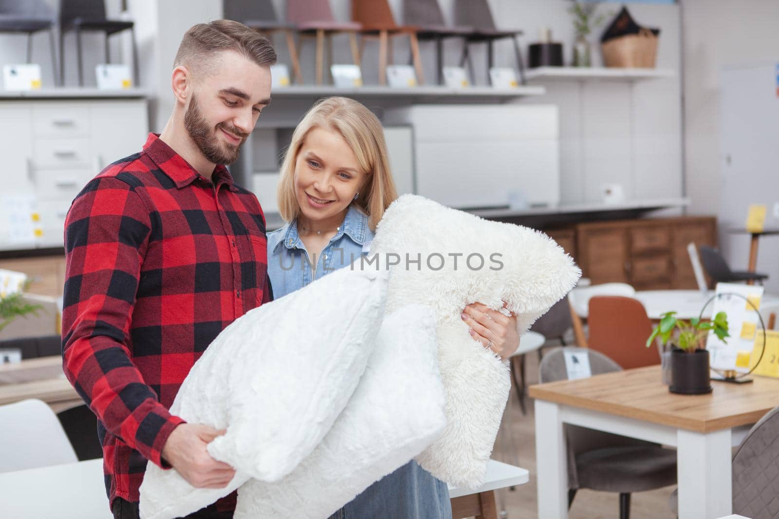 Lovely young couple shopping for beddings together at home goods store, copy space. Beautiful woman and her handsome boyfriend examining pillows on sale