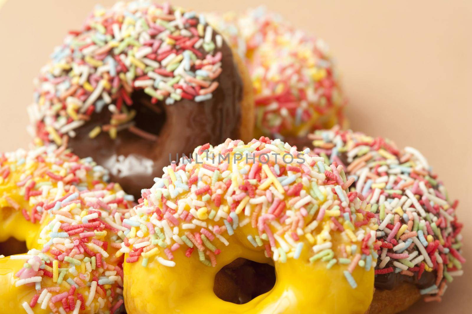 Doughnut assortment with colorful ring donuts glazed with chocolate, lemon and orange icing covered in multicolored candy sprinkles