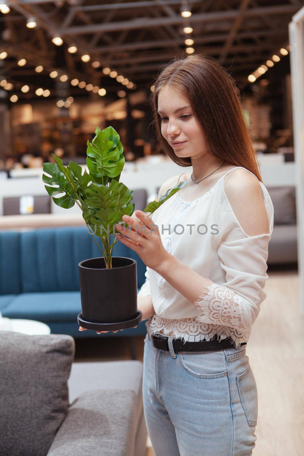 Vertical shot of a young woman buying potted plant at home goods store