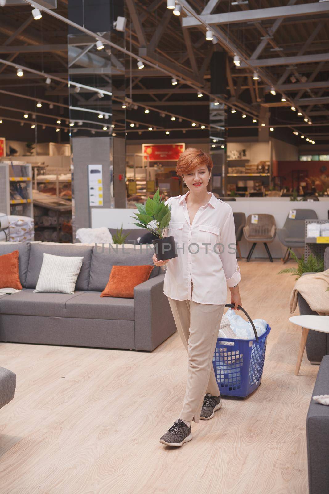 Vertical shot of a female customer carrying potted plant, shopping at home goods store