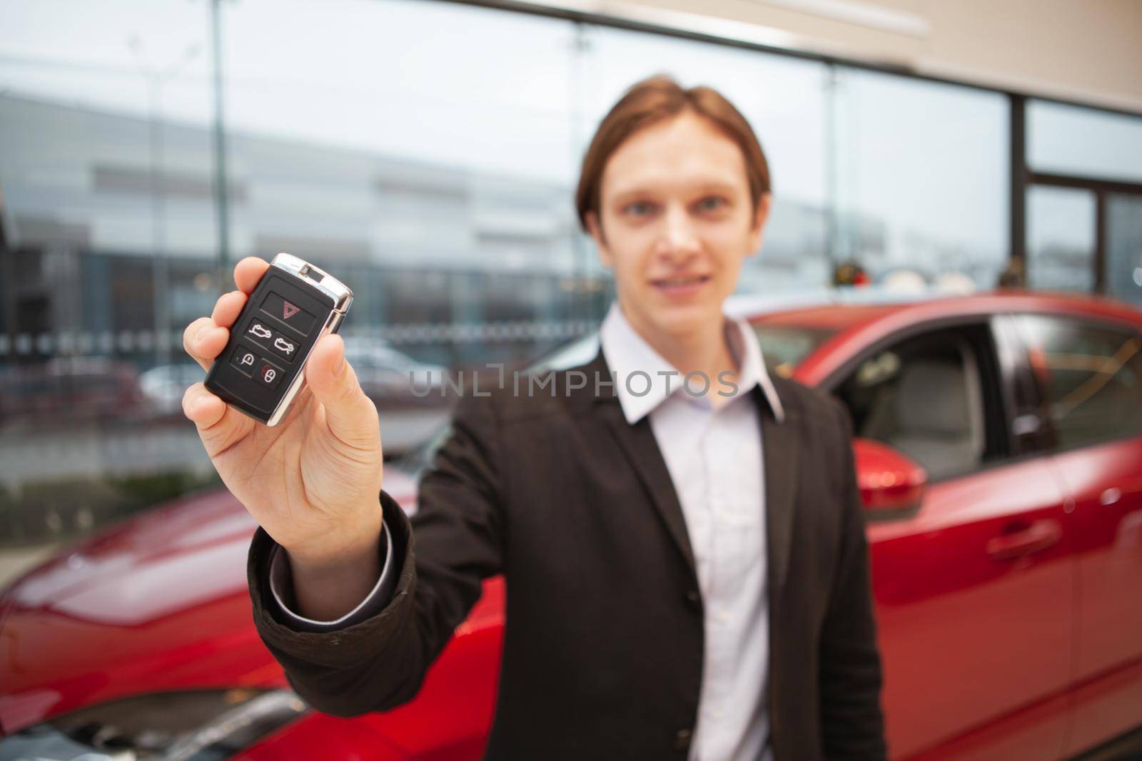 Selective focus on car key in the hand of a cheerful young man at the dealership