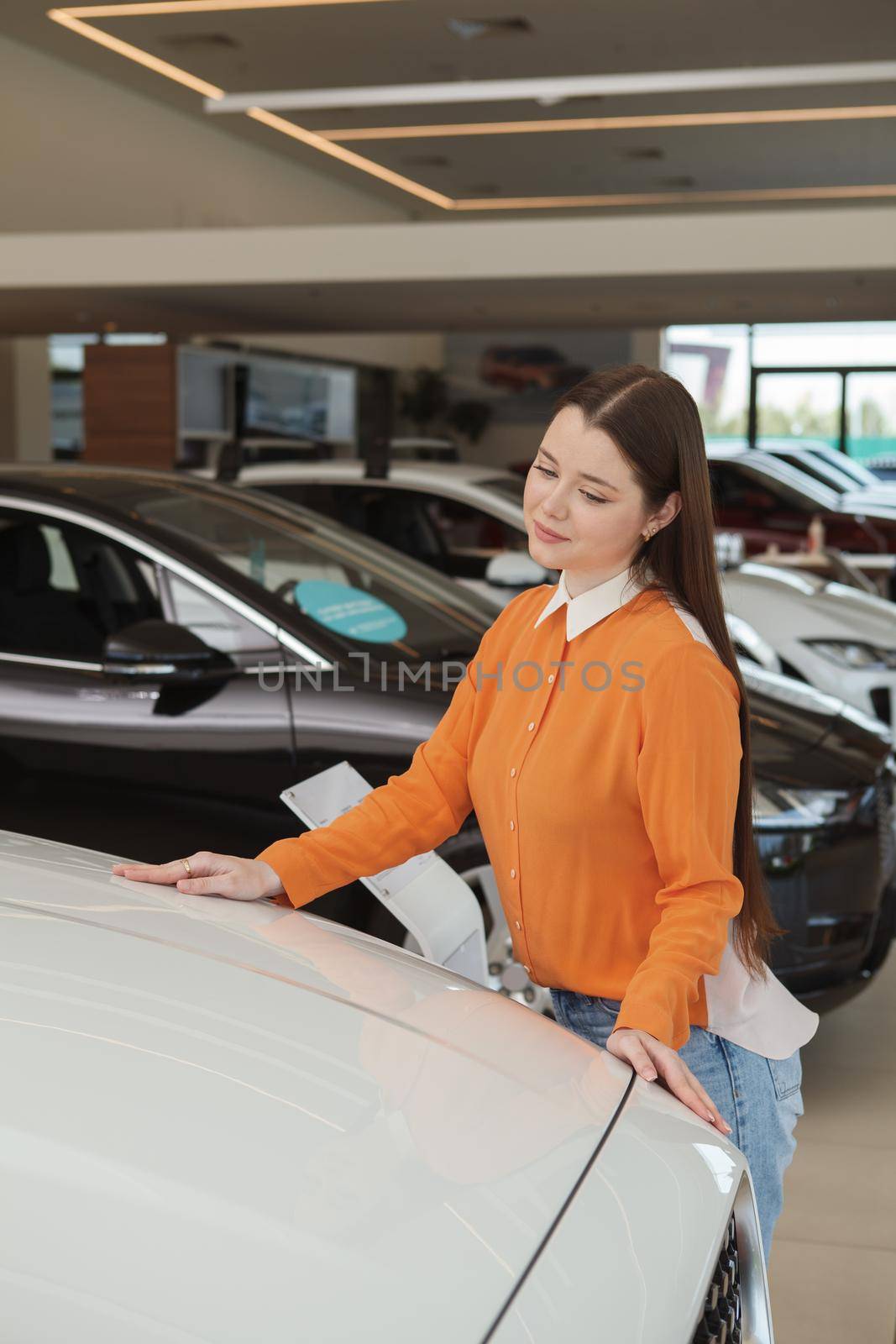 Vertical shot of a female customer choosing new car to buy at the dealership