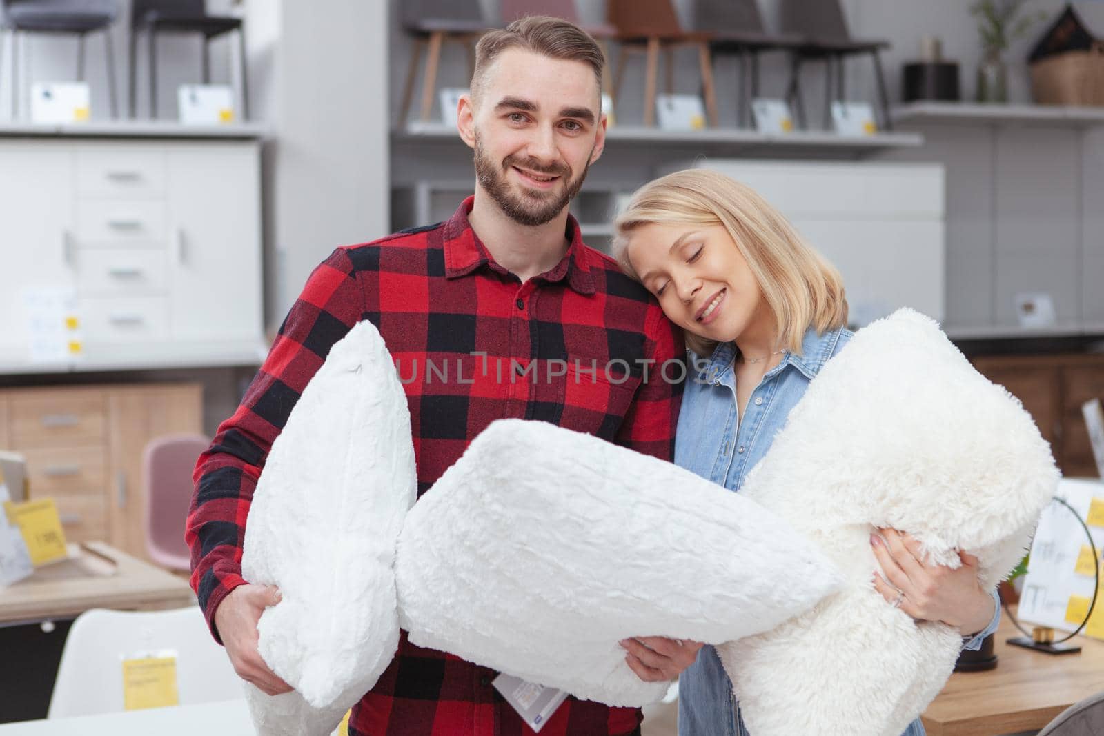 Happy young ouple buying new pillows at furnishings store. Charming young husband and wife enjoying shopping for their new apartment