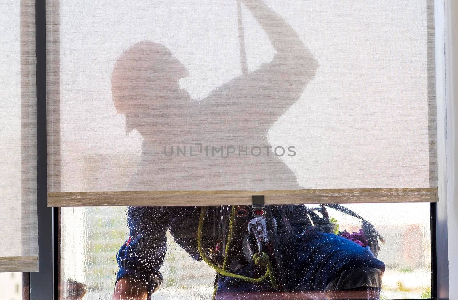 Silhouette of a rope access glass cleaner working at heights.