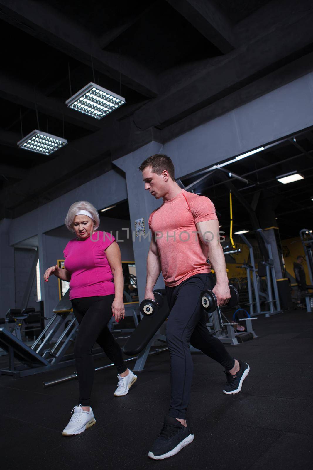 Full length shot of a senior woman learning lunges exercise with personal trainer at the gym