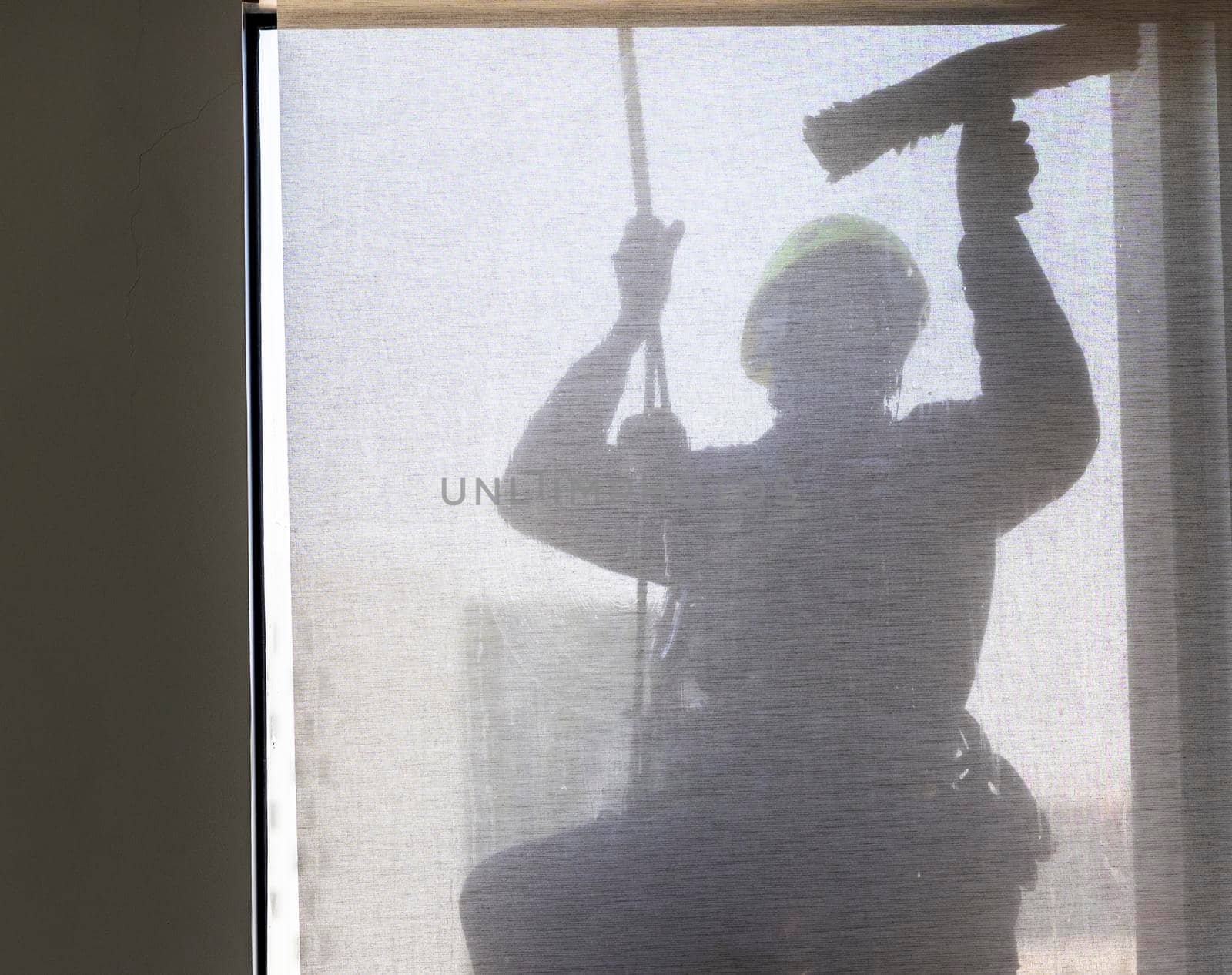 Silhouette of a rope access glass cleaner working at heights.