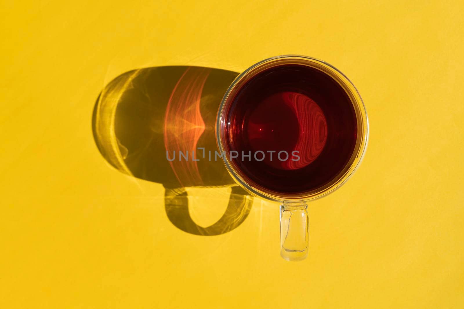 a mug of tea with a hard shadow on a yellow background. photo