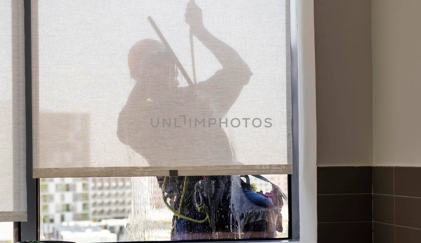 Silhouette of a rope access glass cleaner working at heights.