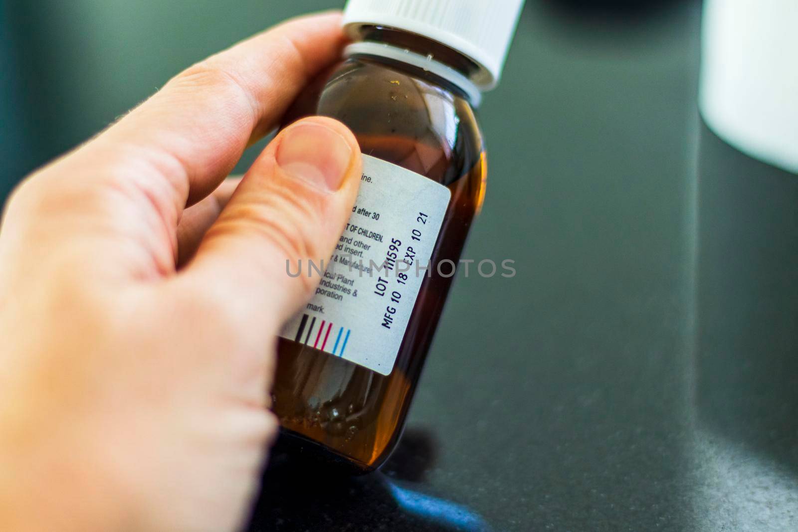 Close up shot of a hand holding a bottle with medicine with expired date. Healthcare by pazemin