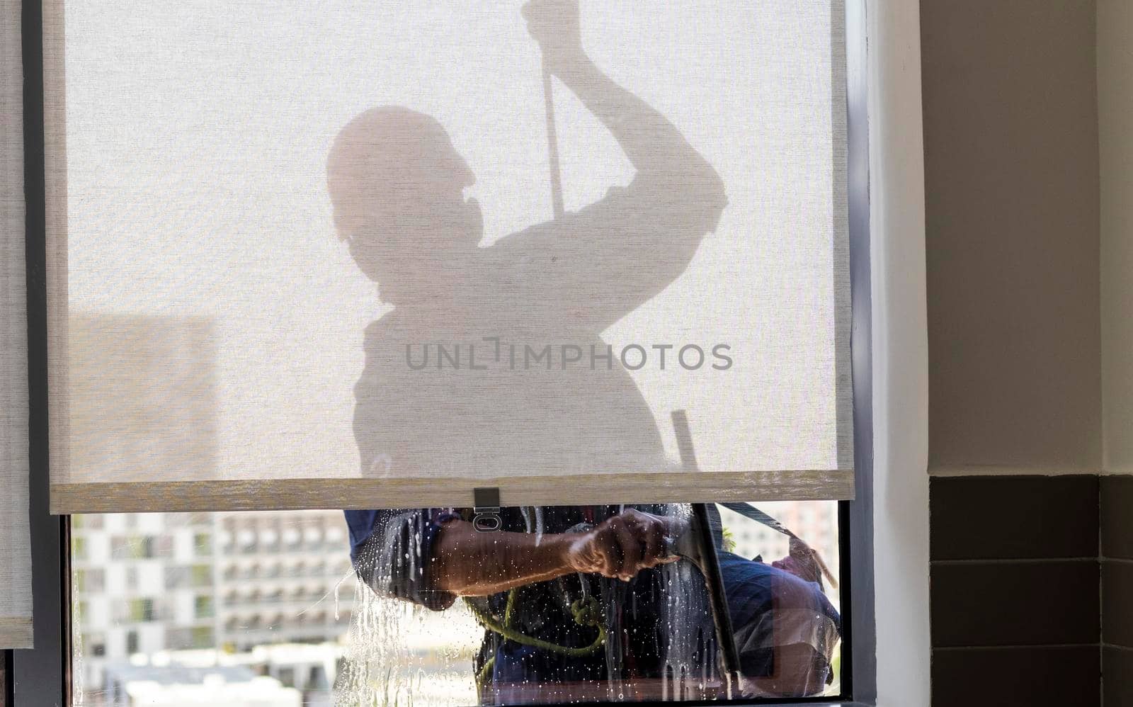 Silhouette of a rope access glass cleaner working at heights.