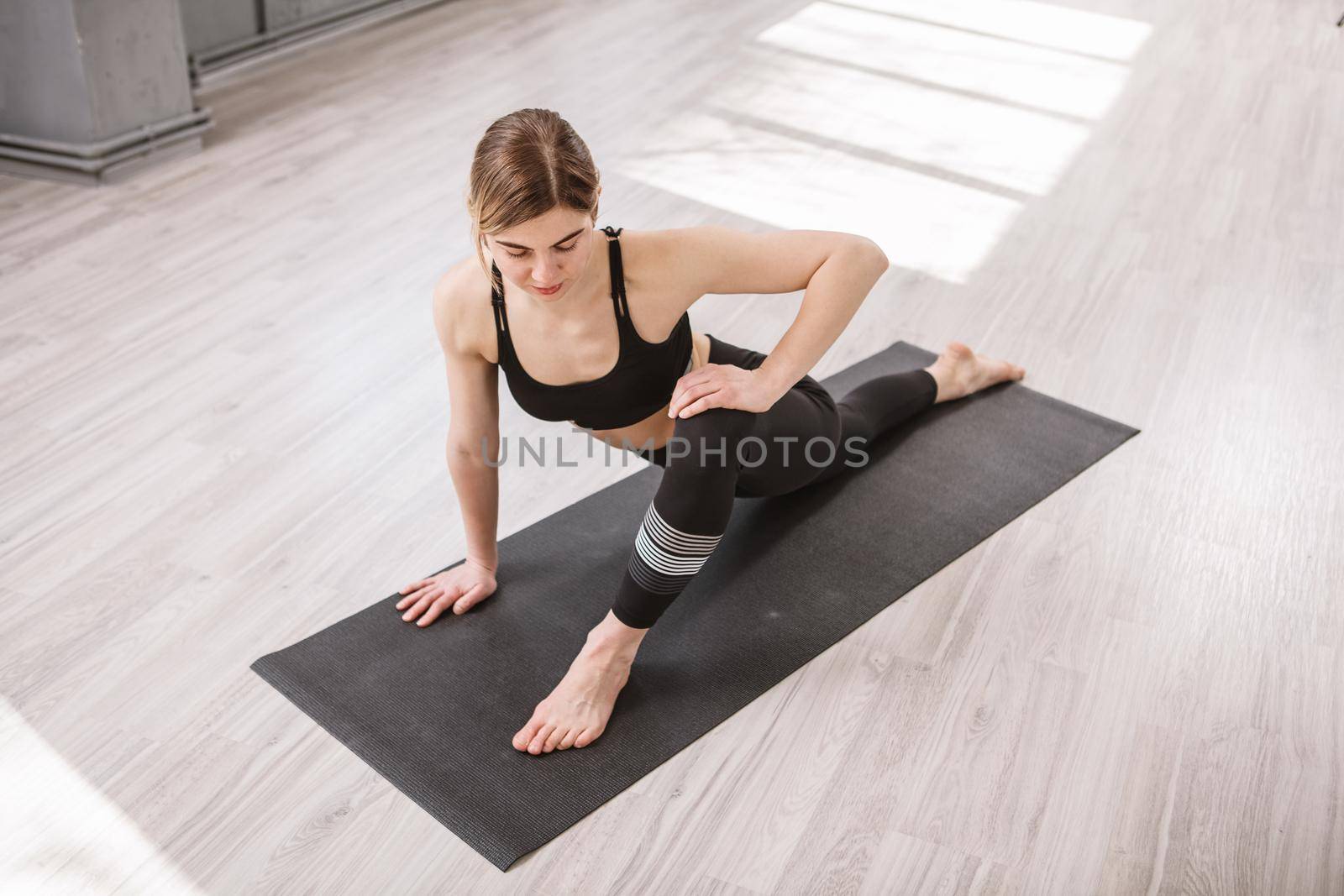 Top view shot of a flexible female gymnast stretching at yoga studio