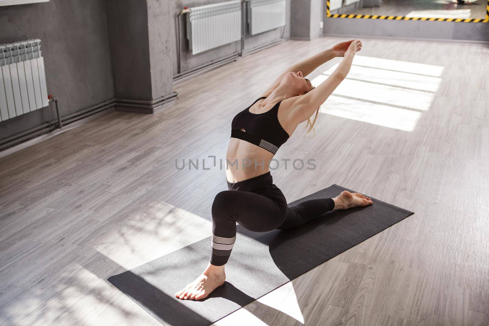 Flexible woman doing stretching yoga workout at sport studio, copy space