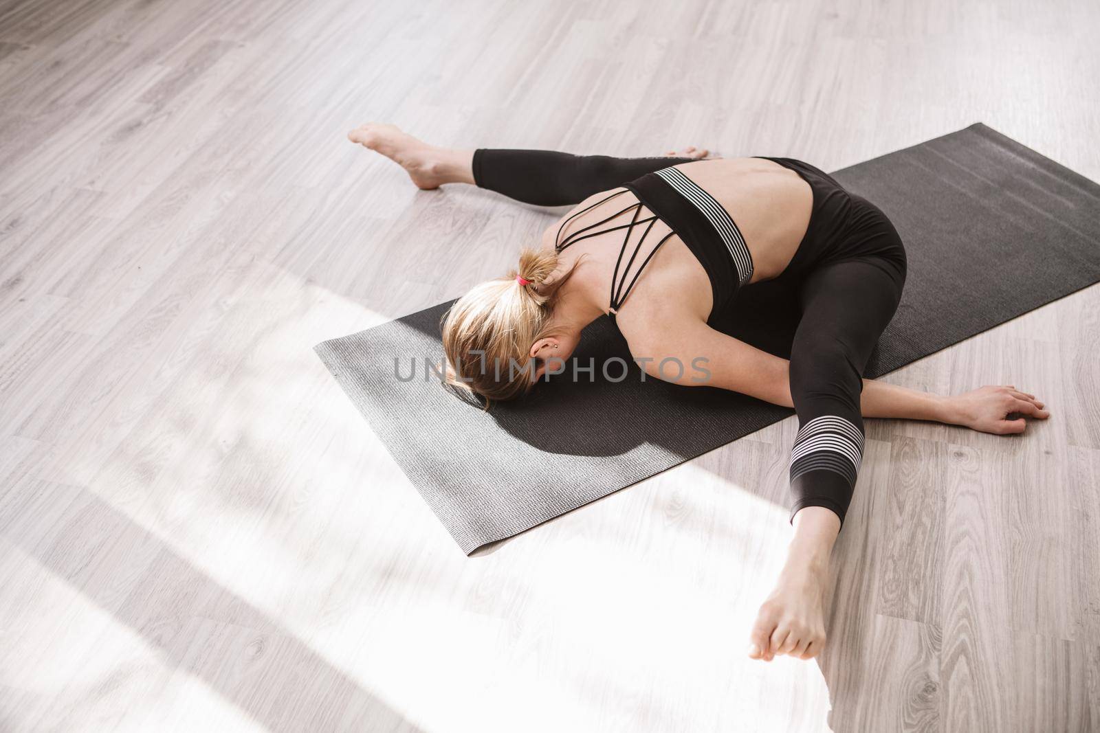 Top view shot of a flexible female gymnast stretching on gym floor, copy space