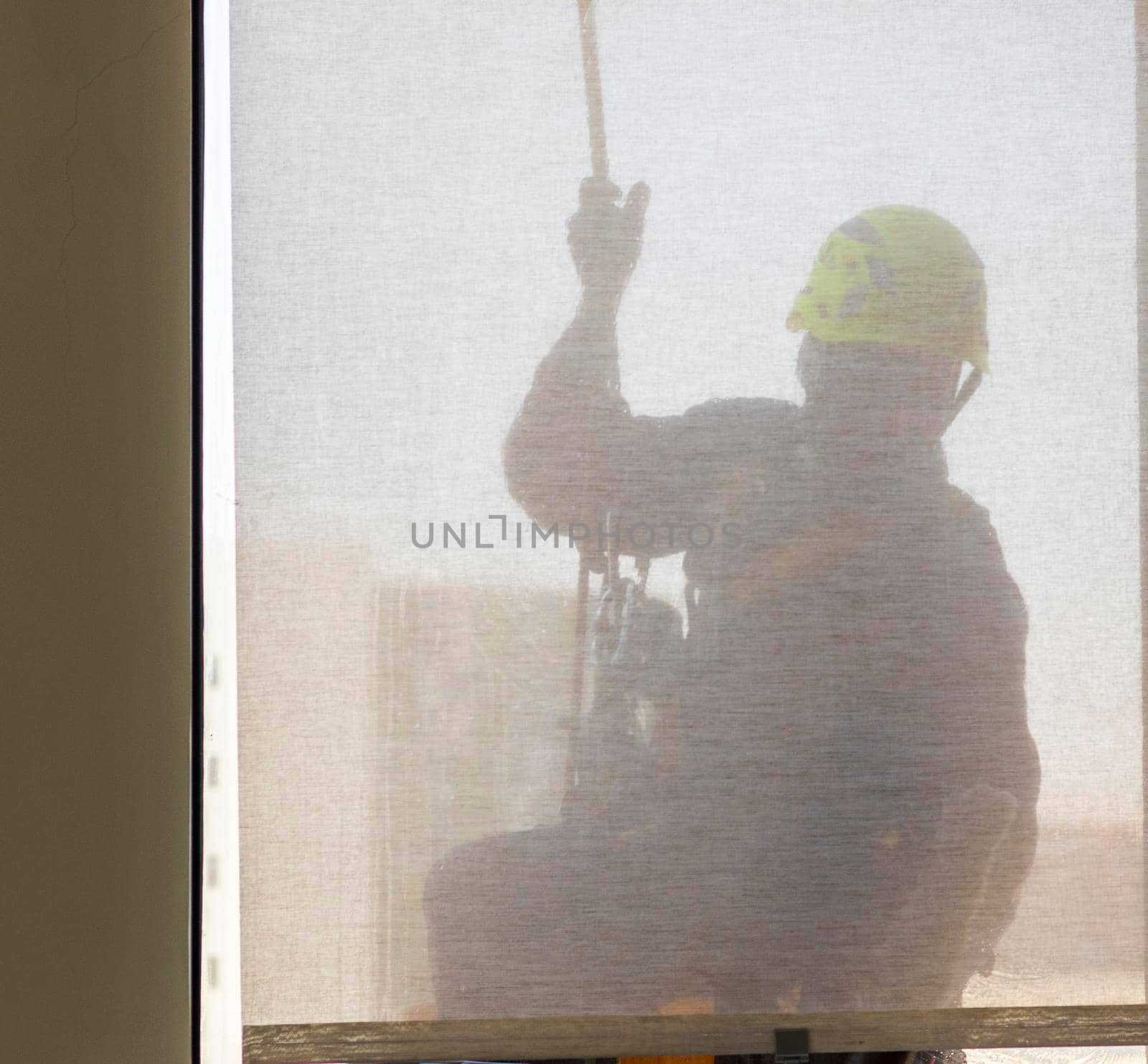 Silhouette of a rope access glass cleaner working at heights.