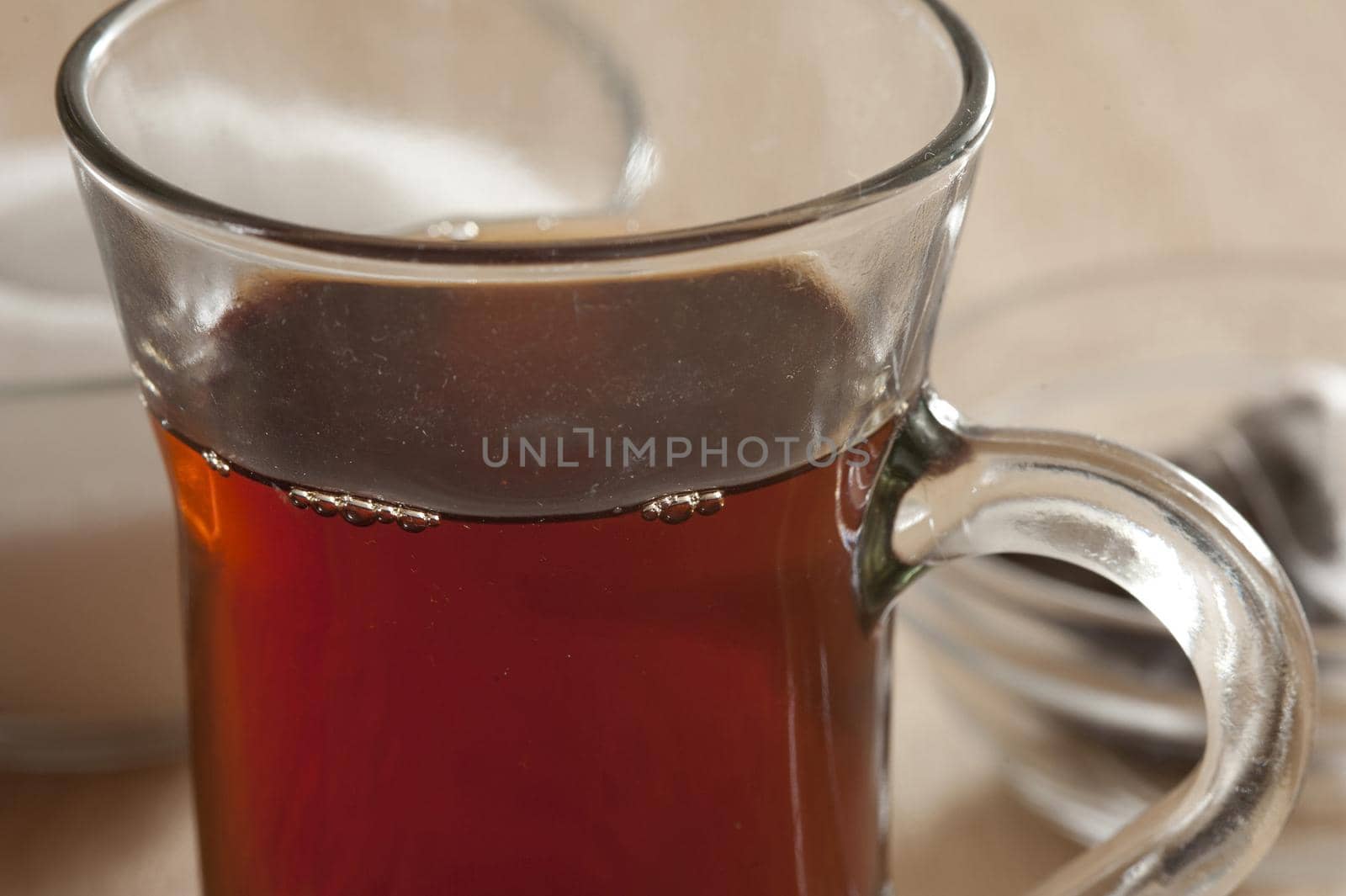 Glass mug of freshly brewed hot black tea , close up view to the rim of the glass and top of the beverage