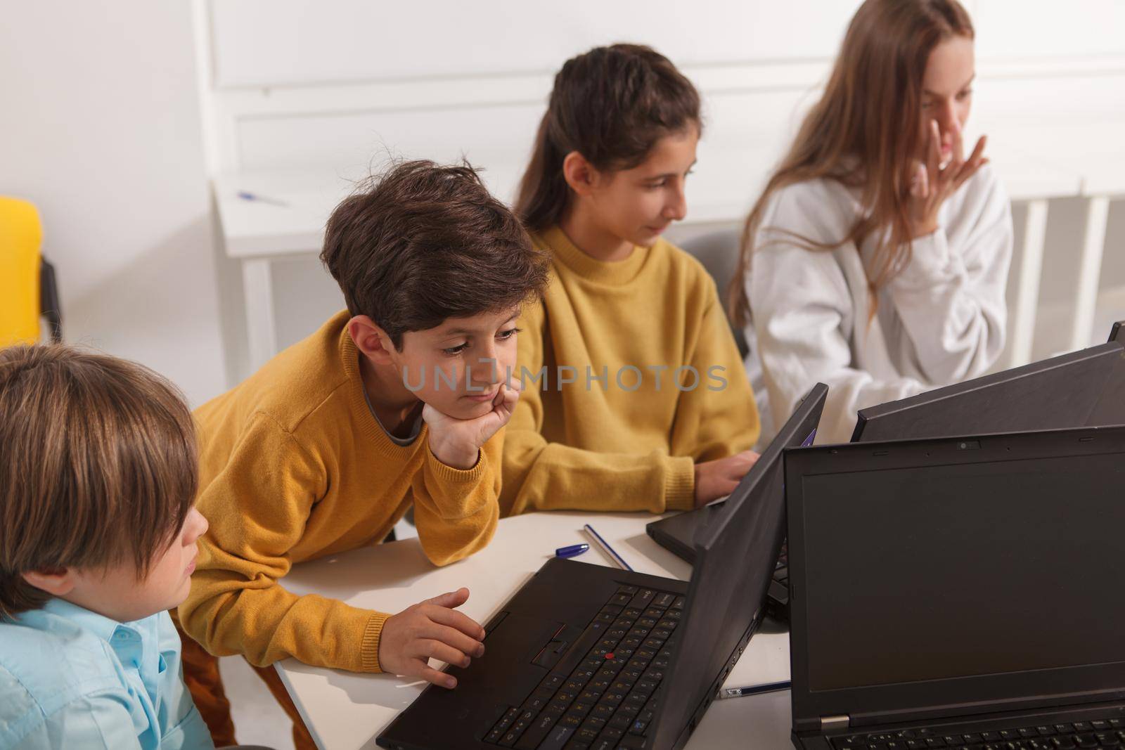 Diverse group of kids working on laptops on computer school lesson