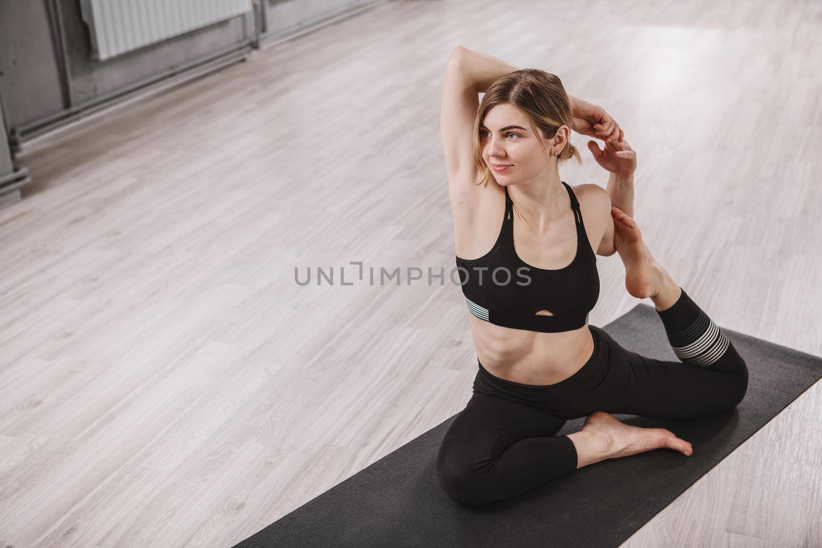 Lovely healthy young woman practicing yoga at sport studio, copy space