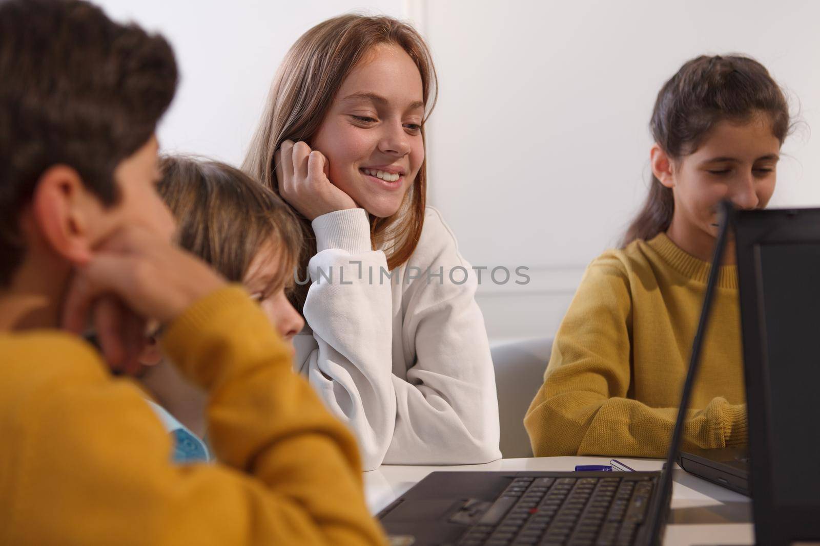 Charming teenage female student smiling, enjoying working with her classmates on a project